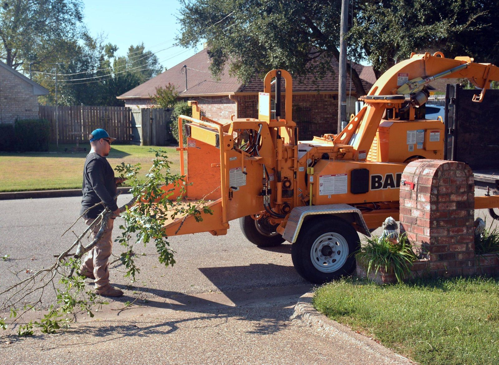 A tree care crew member with a wood chipper on a residential street during cleanup
